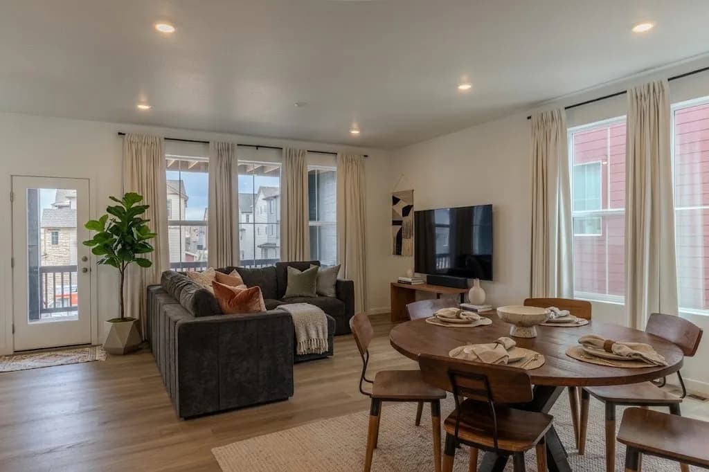 Bright living and dining room with an open floor plan, large windows, and neutral modern furniture — the kind of listing photo an agent would post to Instagram