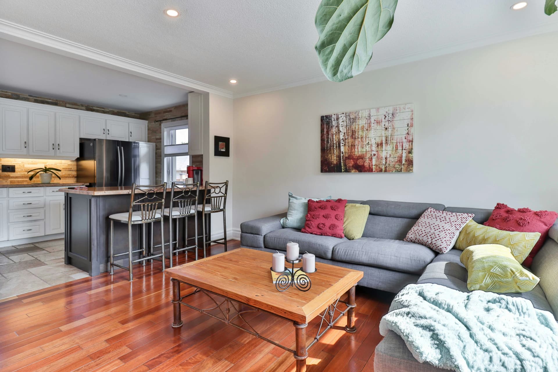 Open-concept living room and kitchen with cherry hardwood floors and a gray sectional sofa