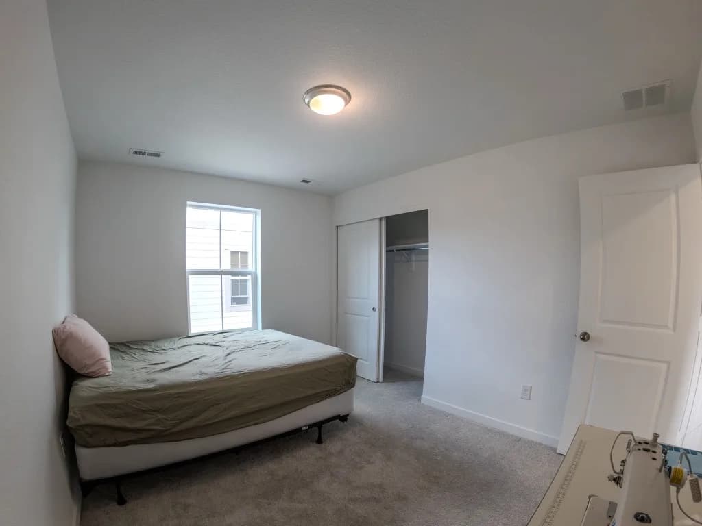 Empty primary bedroom with a bare mattress before virtual staging