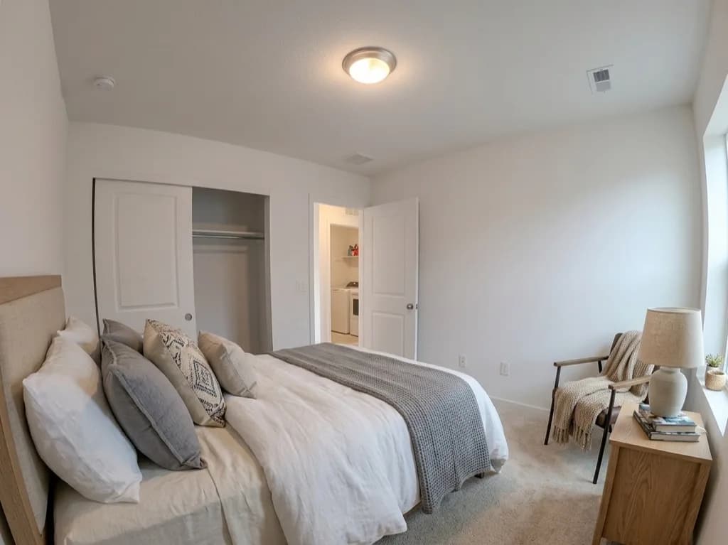 Secondary bedroom virtually staged with a light-wood bed frame, chair, and nightstand