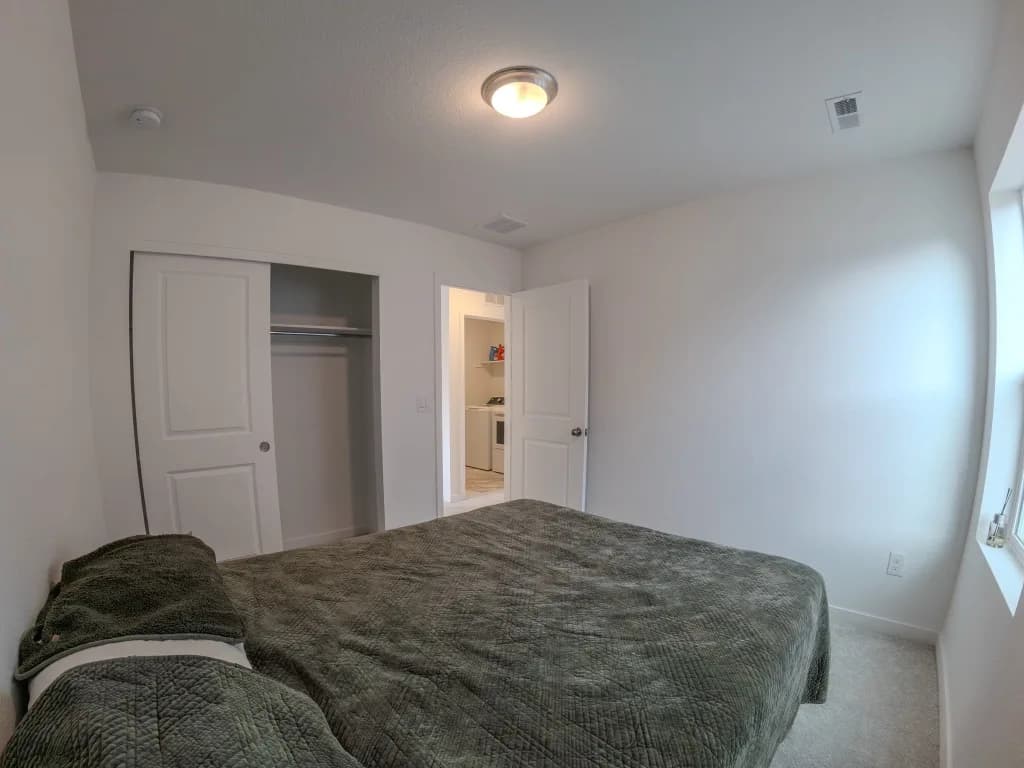 Empty secondary bedroom with a bare mattress before virtual staging